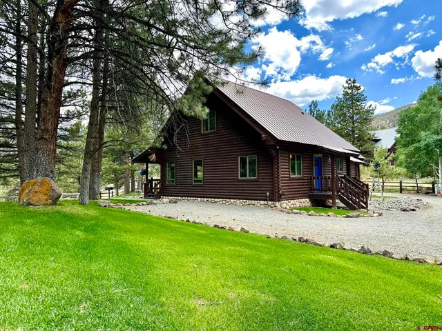 a front view of a house with a garden and trees