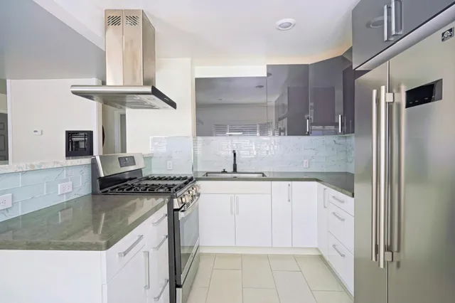 a kitchen with stainless steel appliances granite countertop a sink a stove and a refrigerator