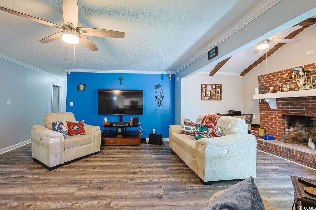 1704 Sherwood Drive Conway, SC 29526 - Photo 13 of 32 Living area featuring ceiling fan, ornamental molding, wood finished floors, vaulted ceiling, and a brick fireplace