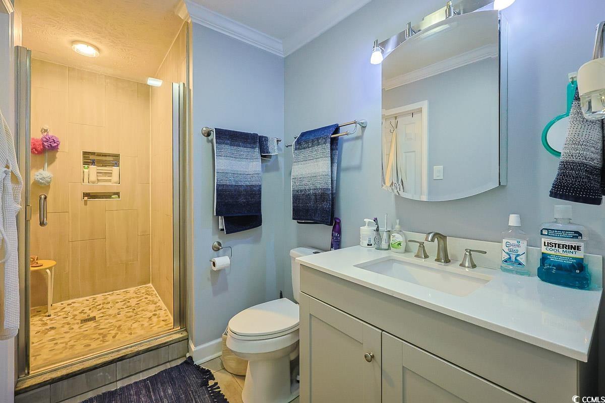 1704 Sherwood Drive Conway, SC 29526 - Photo 17 of 32 Bathroom featuring a stall shower, vanity, crown molding, and light tile patterned floors