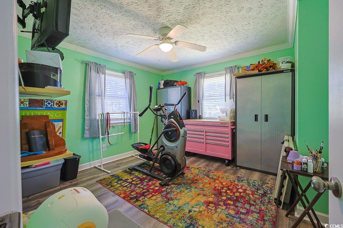 1704 Sherwood Drive Conway, SC 29526 - Photo 18 of 32 Workout area featuring crown molding, a textured ceiling, dark wood-style flooring, and ceiling fan