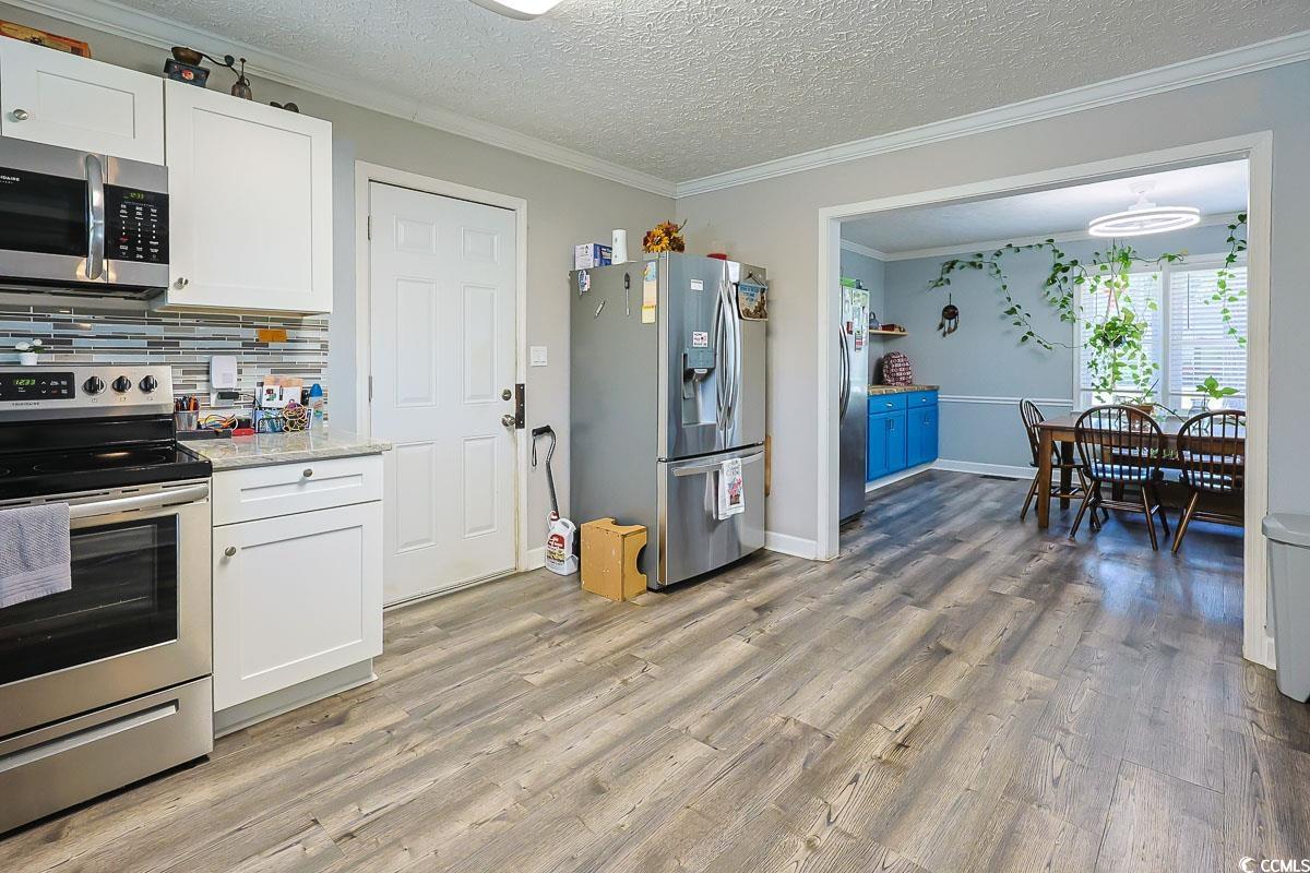 1704 Sherwood Drive Conway, SC 29526 - Photo 5 of 32 Kitchen with appliances with stainless steel finishes, a textured ceiling, white cabinetry, ornamental molding, and decorative backsplash