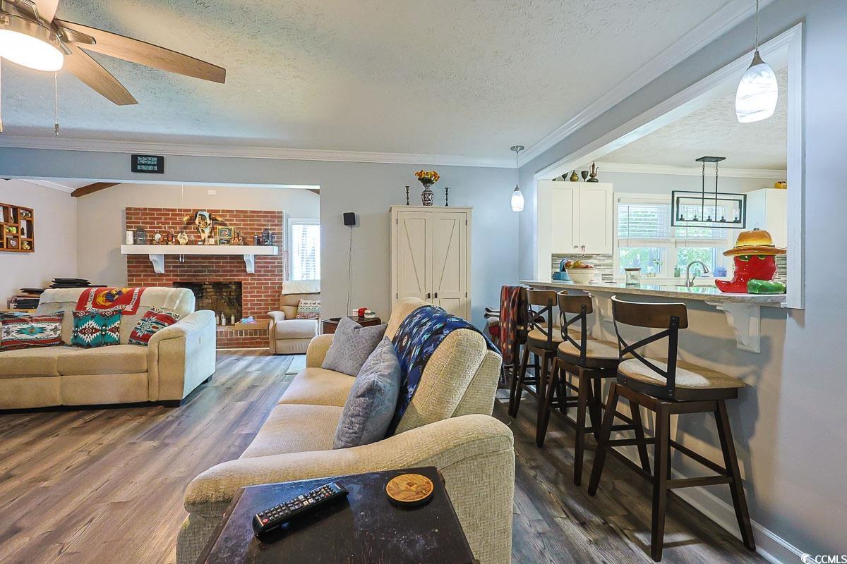 1704 Sherwood Drive Conway, SC 29526 - Photo 10 of 32 Living area with crown molding, a textured ceiling, dark wood-style floors, healthy amount of natural light, and a fireplace