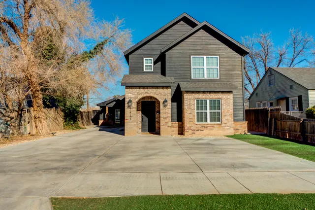 a view of a house with a yard and large trees