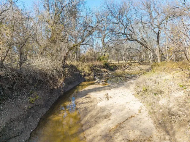 a view of dirt field with trees in the background