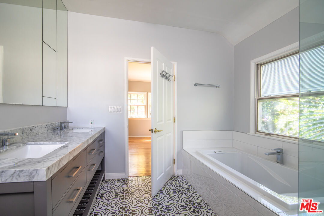 11144 Valley Spring Place Studio City, CA 91602 - Photo 17 of 36 a spacious bathroom with a granite countertop tub sink and mirror
