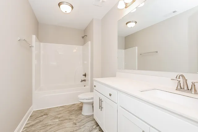 a bathroom with a granite countertop sink a toilet and shower