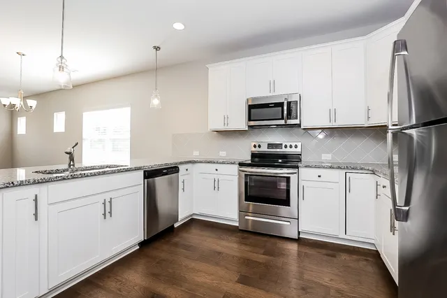 a kitchen with stainless steel appliances granite countertop a stove a sink and a refrigerator
