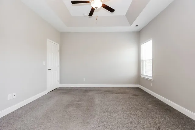 an empty room with a ceiling fan and window