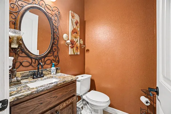 a bathroom with a granite countertop toilet sink and mirror
