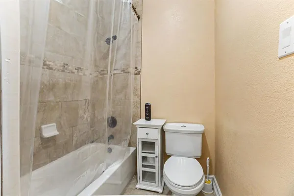 a white toilet sitting next to a bath tub and a shower