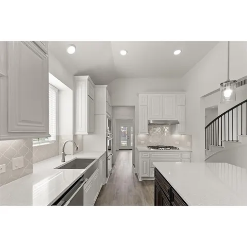 a kitchen with a sink dishwasher a stove a refrigerator and white cabinets with wooden floor