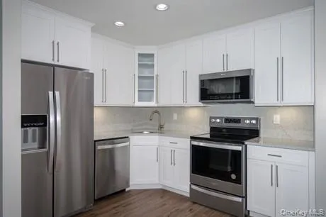 a kitchen with cabinets stainless steel appliances and wooden floor