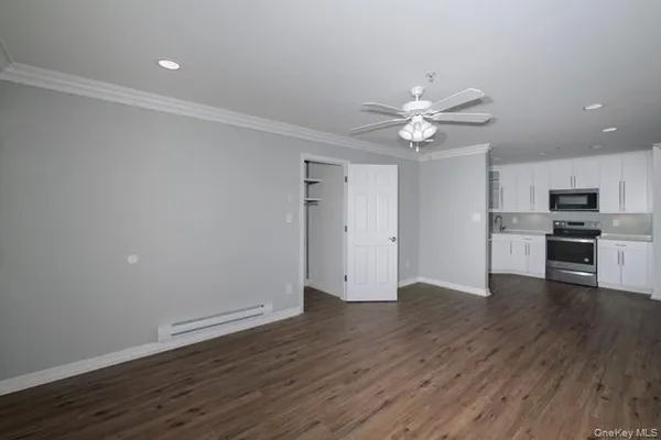 a view of an empty room with wooden floor and a ceiling fan