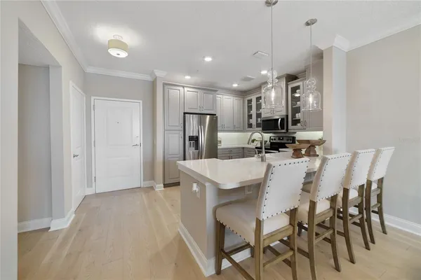 a kitchen with kitchen island a dining table chairs refrigerator and cabinets