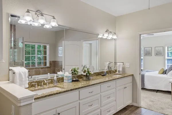 a bathroom with double vanity sinks a vanity a lamp and a mirror