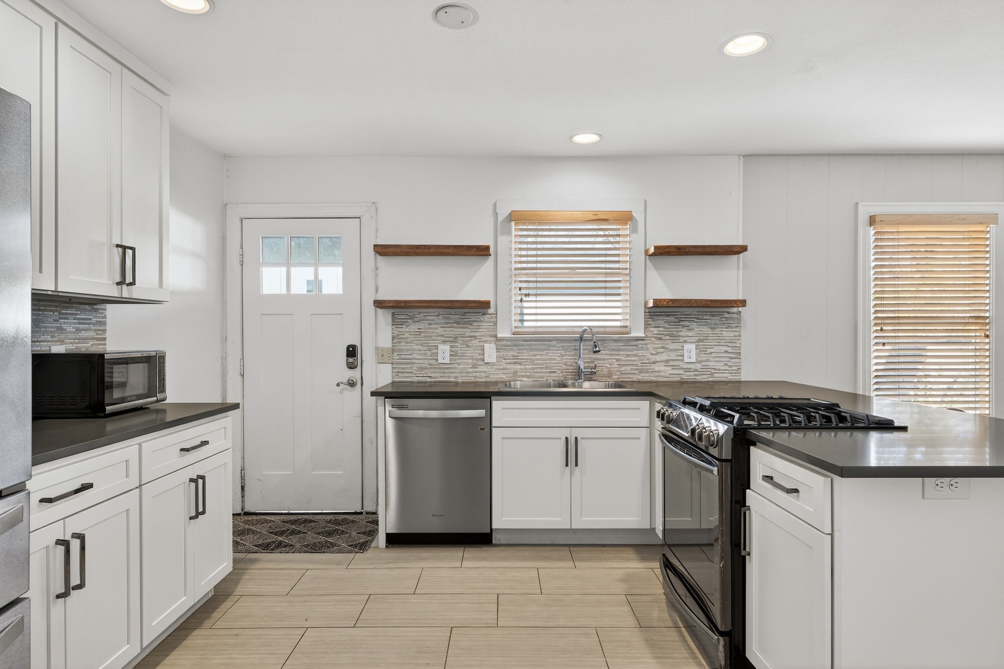 609 Fletcher Street Austin, TX 78704 - Photo 10 of 25 a kitchen with granite countertop white cabinets stainless steel appliances a sink and a window