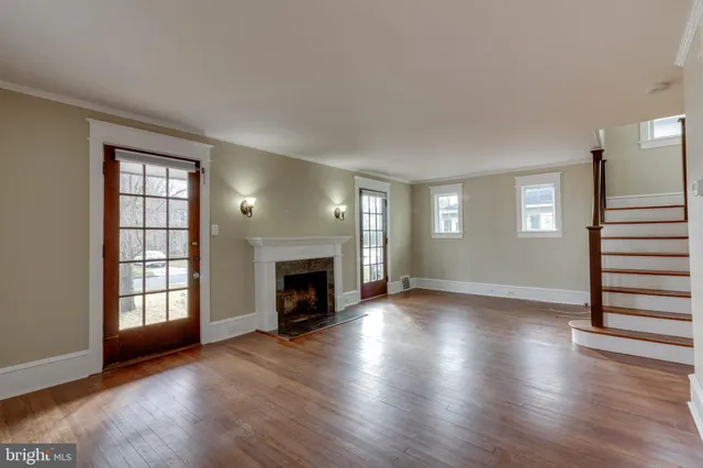 an empty room with wooden floor fireplace and windows