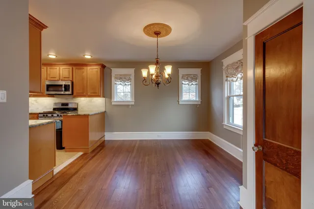 a kitchen with stainless steel appliances granite countertop a refrigerator a stove top oven and a wooden floors