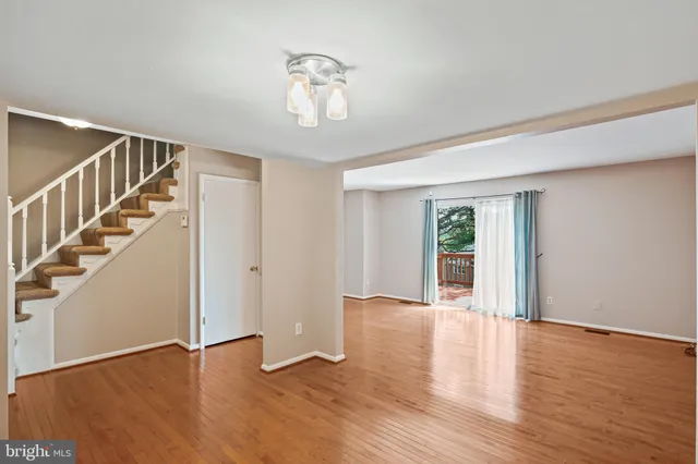 a view of an empty room with wooden floor and stairs