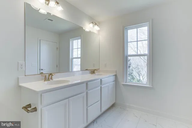 a bathroom with double sink window and a mirror