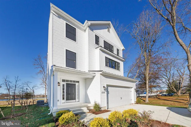 a view of a white house with a large tree