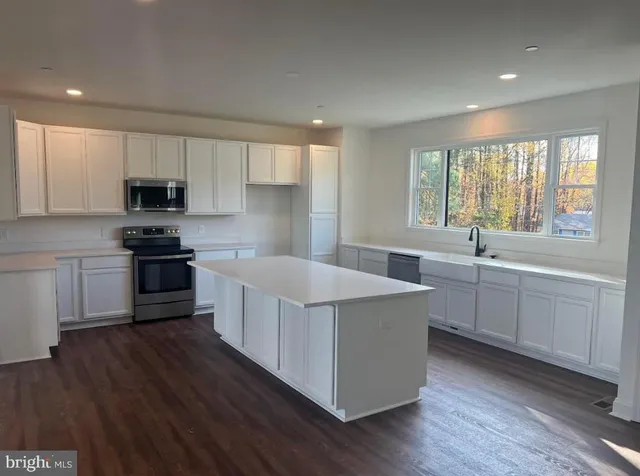 a kitchen with stainless steel appliances a stove a sink a center island and a window