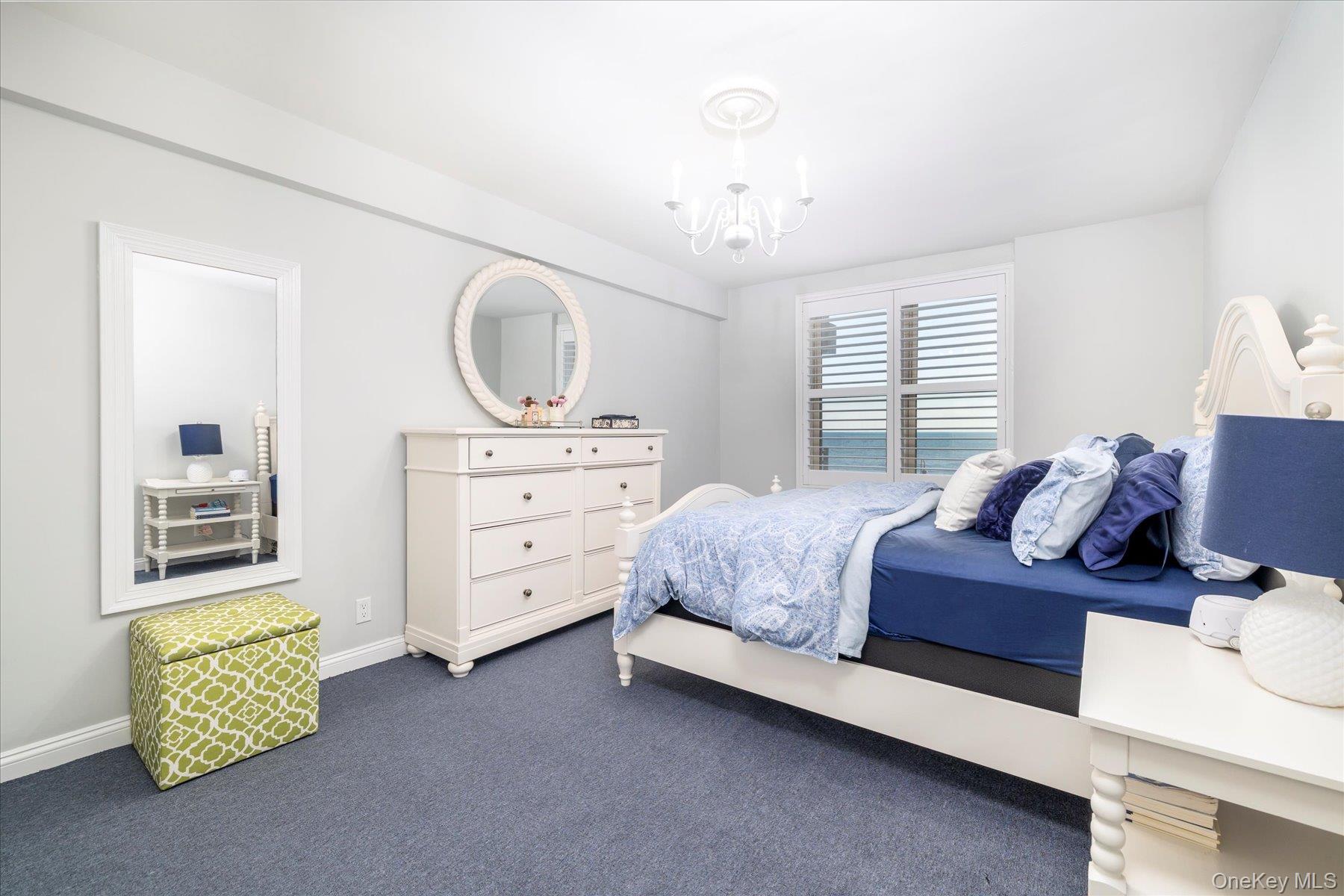 560 West Broadway, Unit 4R Long Beach, NY 11561 - Photo 14 of 26 a spacious bedroom with a bed and a chandelier