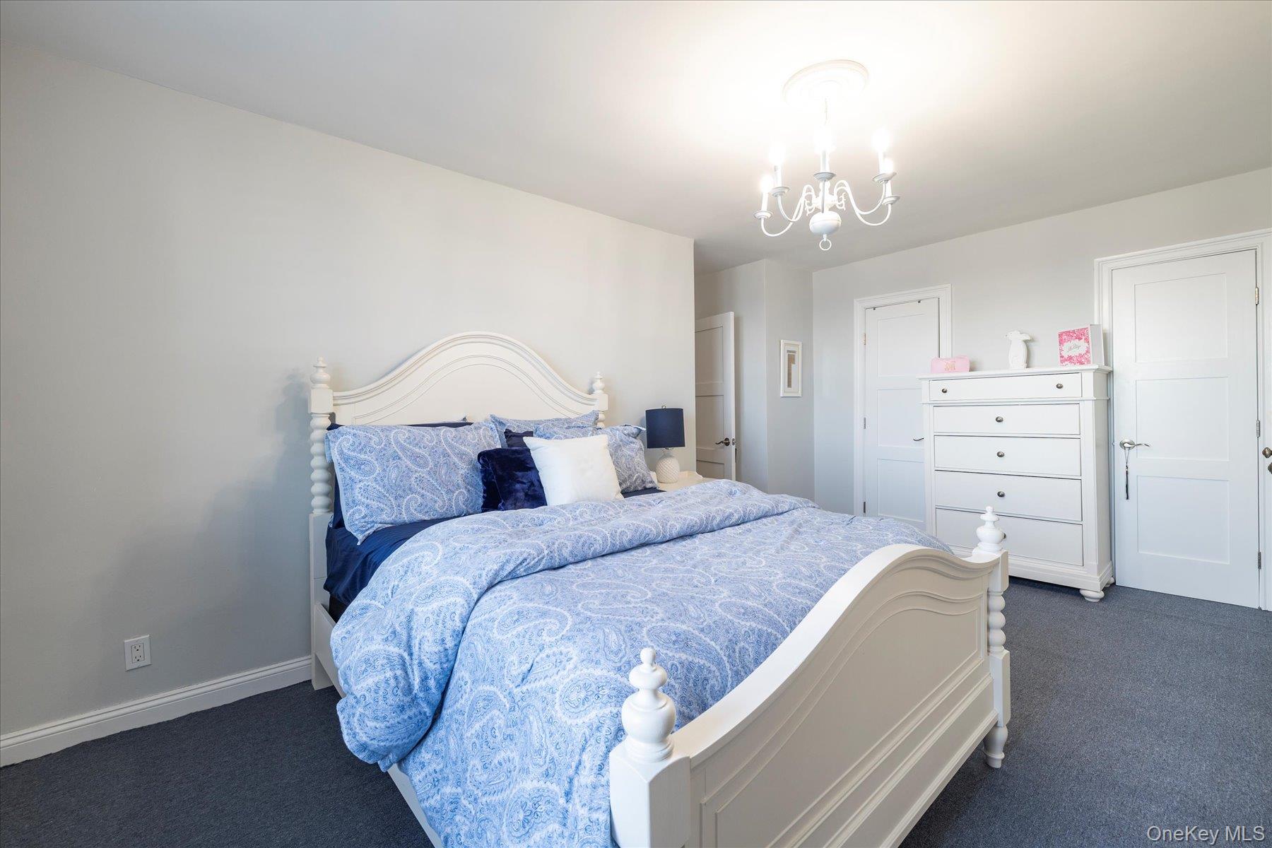 560 West Broadway, Unit 4R Long Beach, NY 11561 - Photo 16 of 26 a bedroom with a bed and a chandelier