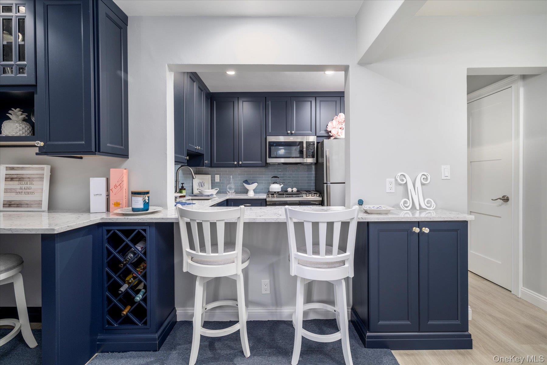 560 West Broadway, Unit 4R Long Beach, NY 11561 - Photo 9 of 26 a kitchen with stainless steel appliances granite countertop a table chairs sink and cabinets