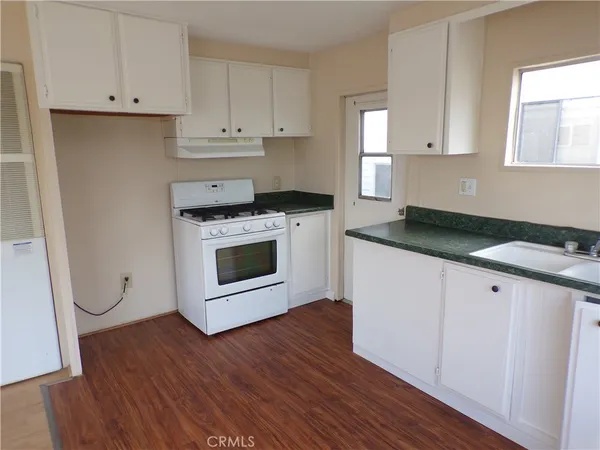 a kitchen with granite countertop a stove a microwave and a hard wood floor
