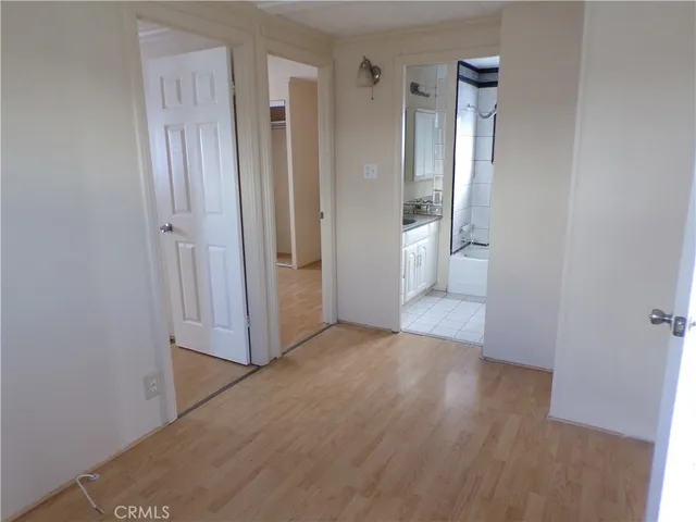 a view of an empty room with wooden floor and a bathroom