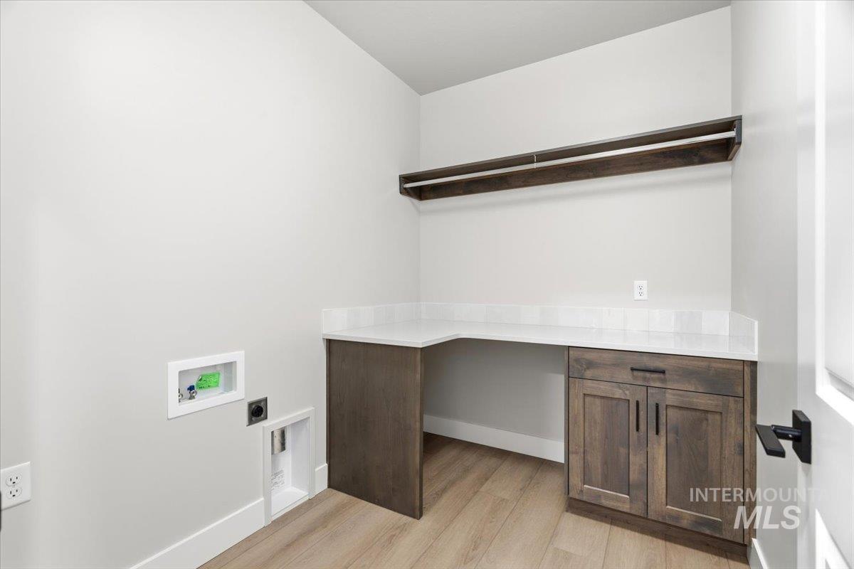 4317 Tropic Way Caldwell, ID 83607 - Photo 38 of 47 Dedicated home office featuring a wood-finish desk with ample workspace, dark wood cabinetry with paneled doors, white quartz countertop, warm wood-finish flooring, and a wall-mounted shelving unit