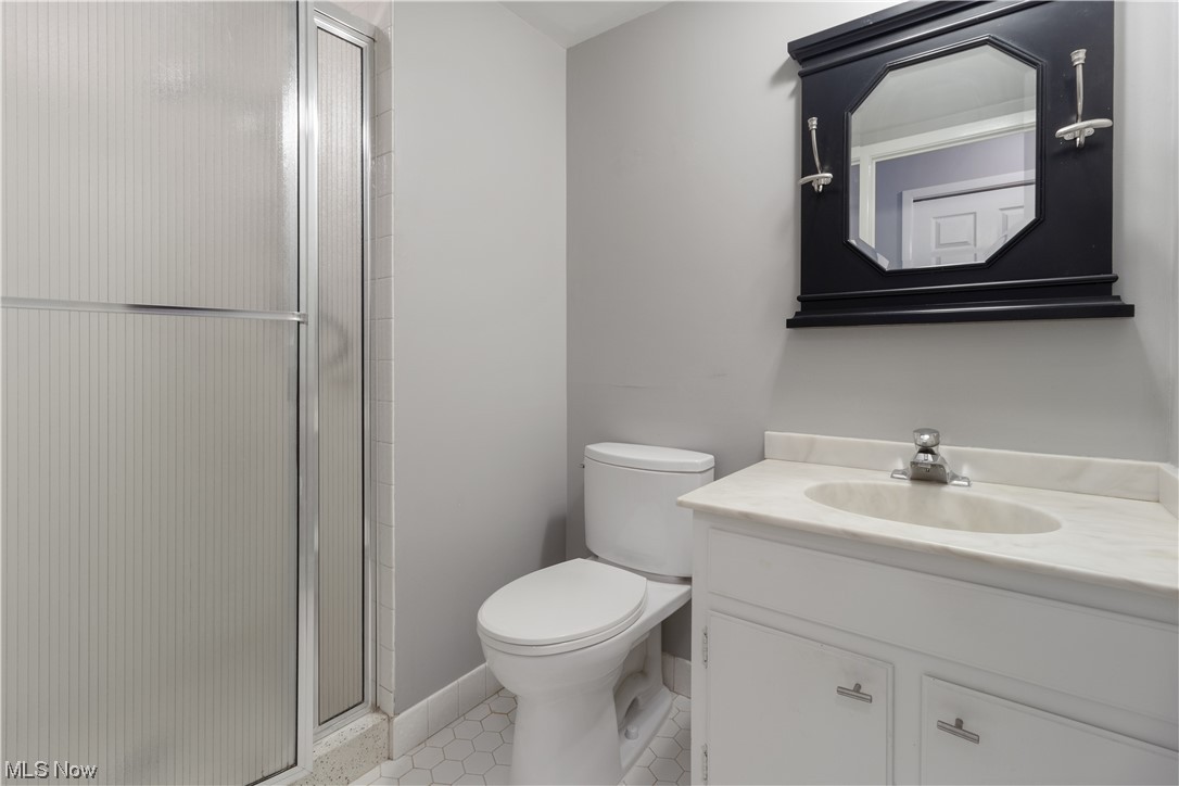 22555 Center Ridge Road, Unit 303 Rocky River, OH 44116 - Photo 23 of 33 Bathroom with vanity, a shower with door, mirror, and light tile flooring