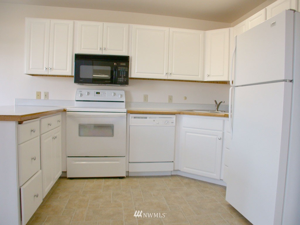2900 Northeast 8th Street Renton, WA 98056 - Photo 5 of 25 a view of a kitchen with white cabinets stainless steel appliances and sink