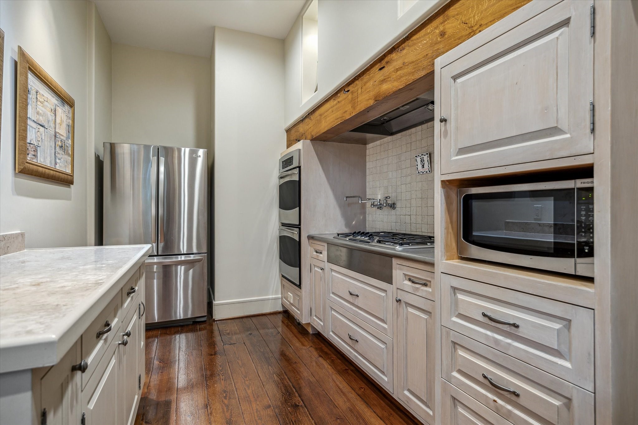 354 Piney Point Road Houston, TX 77024 - Photo 25 of 49 a kitchen with stainless steel appliances white cabinets and wooden floor