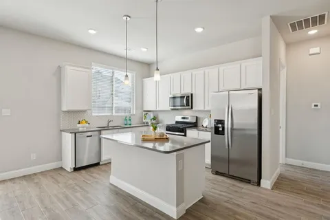 a kitchen with a refrigerator a sink and wooden floor