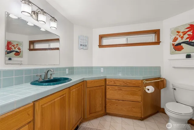 a bathroom with a granite countertop sink a toilet and a mirror