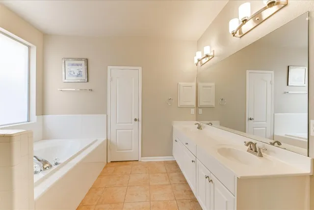a spacious bathroom with a tub sink and mirror