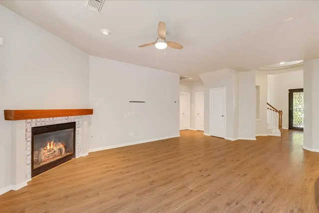a view of an empty room with wooden floor and a fireplace