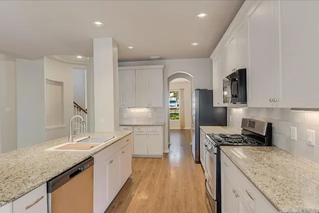 a large kitchen with stainless steel appliances granite countertop a lot of counter space and wooden floors