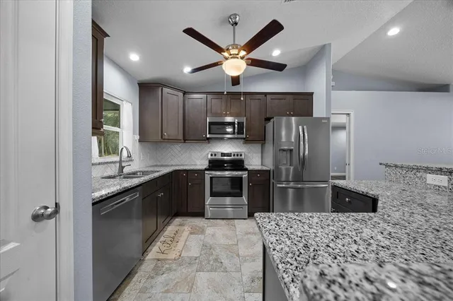 a kitchen with stainless steel appliances granite countertop a refrigerator a stove a sink and dishwasher