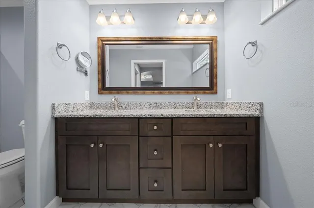 a bathroom with a granite countertop sink a toilet and shower