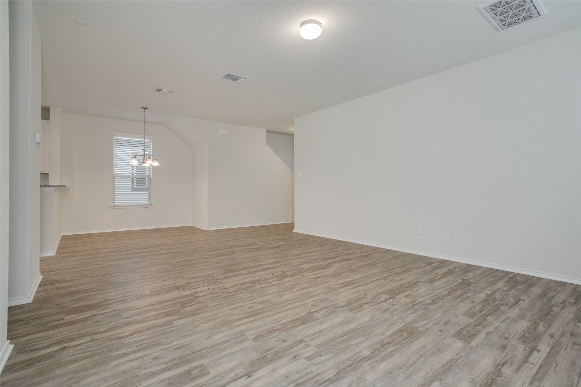 148 Spotted Rail Ridge Leander, TX 78641 - Photo 5 of 31 A spacious, open-concept interior features wood-look flooring and a dining area with an elegant chandelier.