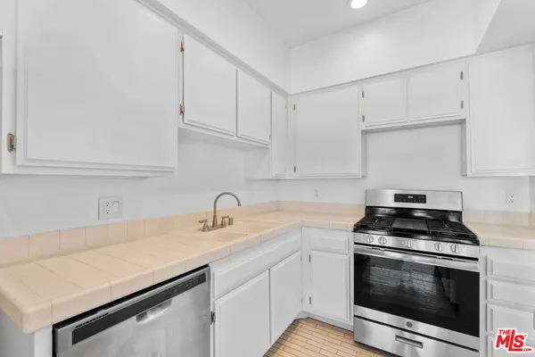 a kitchen with white cabinets stainless steel appliances and sink