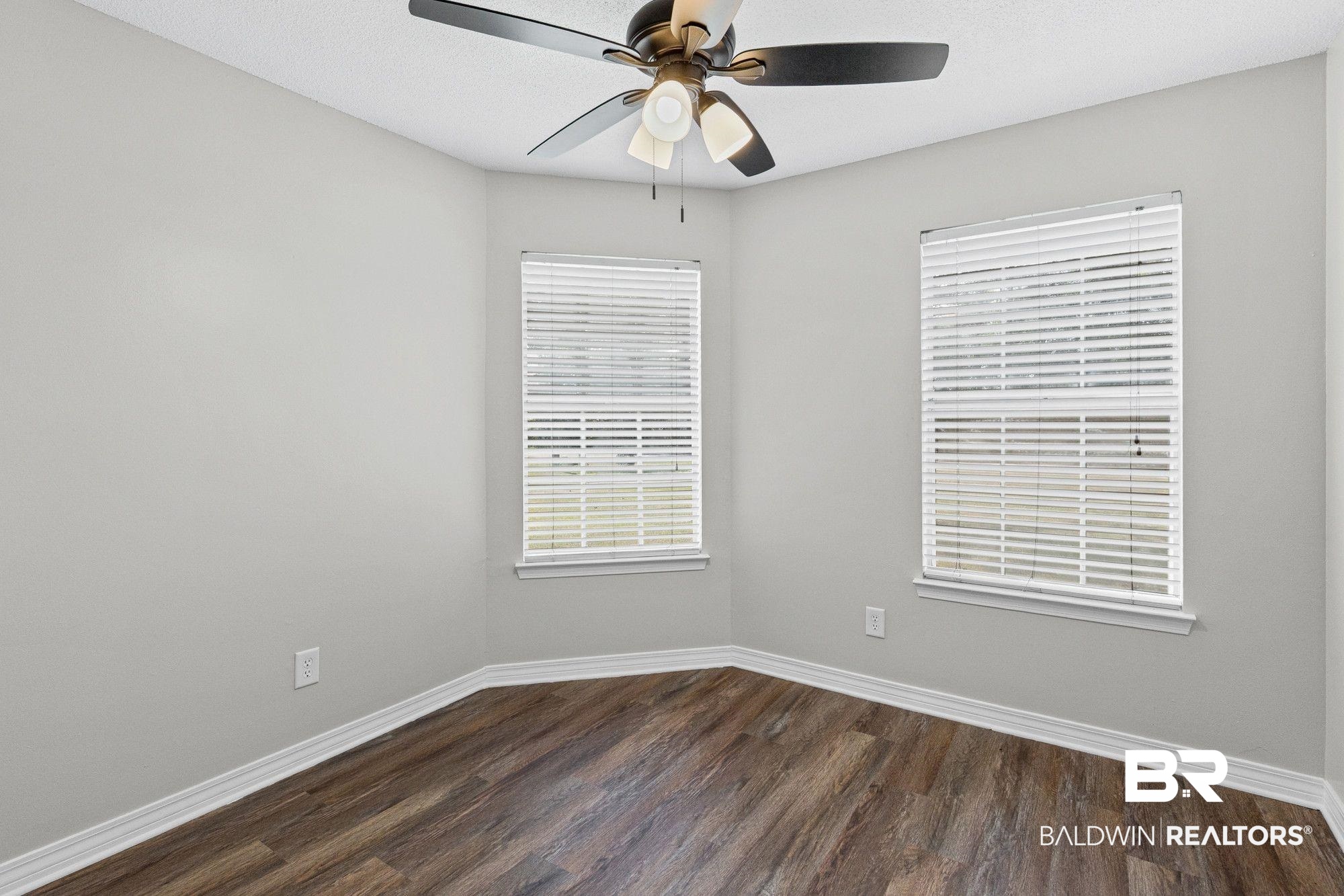 1301 Repoll Road Mobile, AL 36695 - Photo 13 of 21 Room featuring wood-finish flooring, two windows with blinds, a ceiling fan with integrated lighting, and light-toned walls