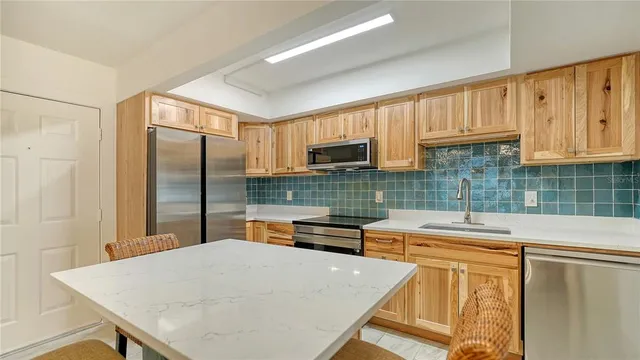 a kitchen with stainless steel appliances a stove a sink a refrigerator white cabinets and wooden floor