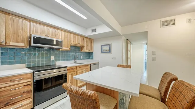 a kitchen with stainless steel appliances a stove a sink refrigerator and a microwave