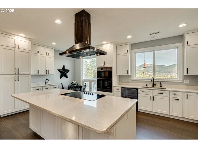 a kitchen with stainless steel appliances a sink a stove a refrigerator cabinets and a window
