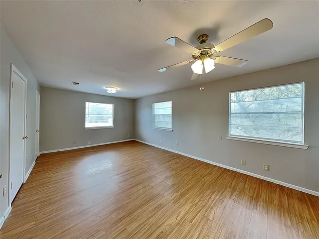 a view of an empty room with window and wooden floor
